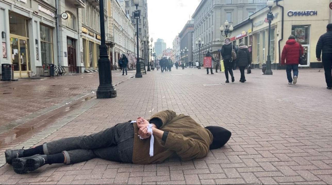 Mosca, un attivista russo protesta a terra e con le mani legate come le vittime di Bucha